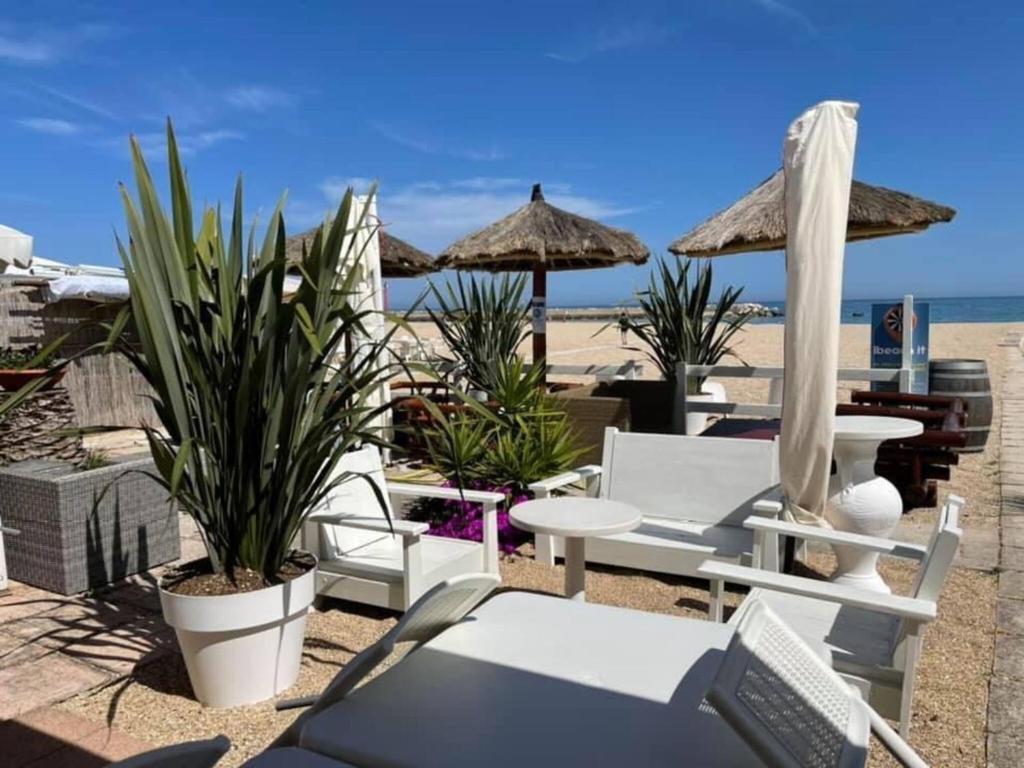 plaży z krzesłami, stołami i parasolami w obiekcie Italian Experience-Numana Suite Apartment w mieście Numana