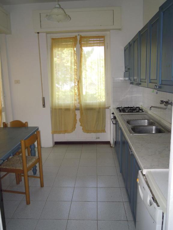 kuchnia z niebieskimi szafkami, umywalką i oknem w obiekcie Italian Experience-Casa Argentario w mieście Giannella