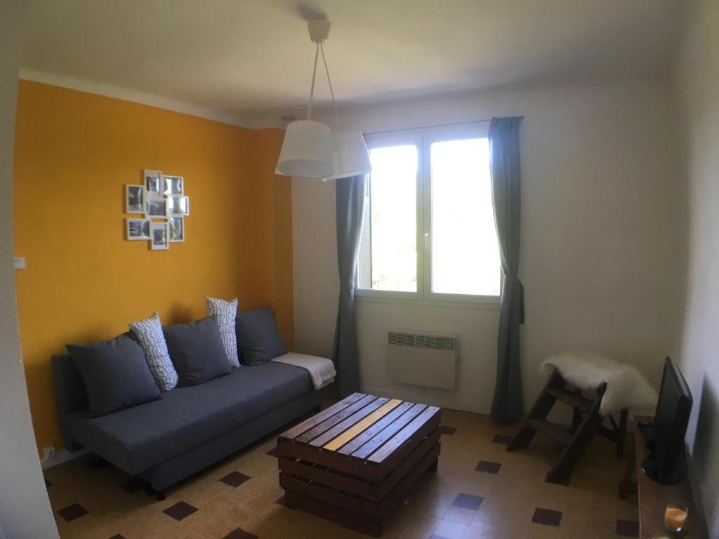 un salon avec un canapé bleu et une fenêtre dans l'établissement Au fil du Chassezac #Miel, à Chambonas