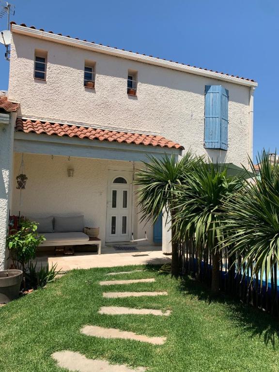 une grande maison blanche avec un banc dans la cour dans l'établissement Villa avec piscine proche de la mer, à Lattes