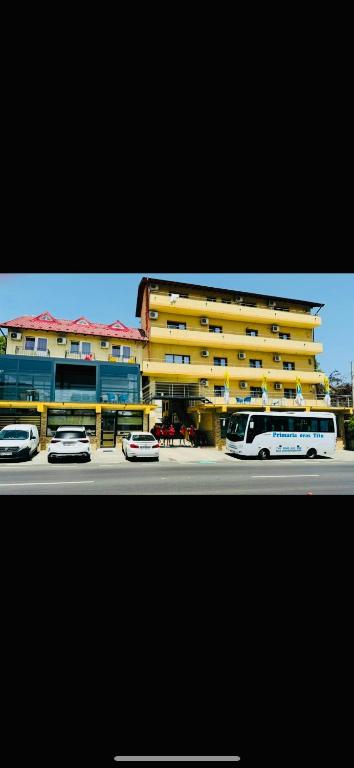 a large yellow building with cars parked in front of it at Pensiunea Domneasca in Piteşti