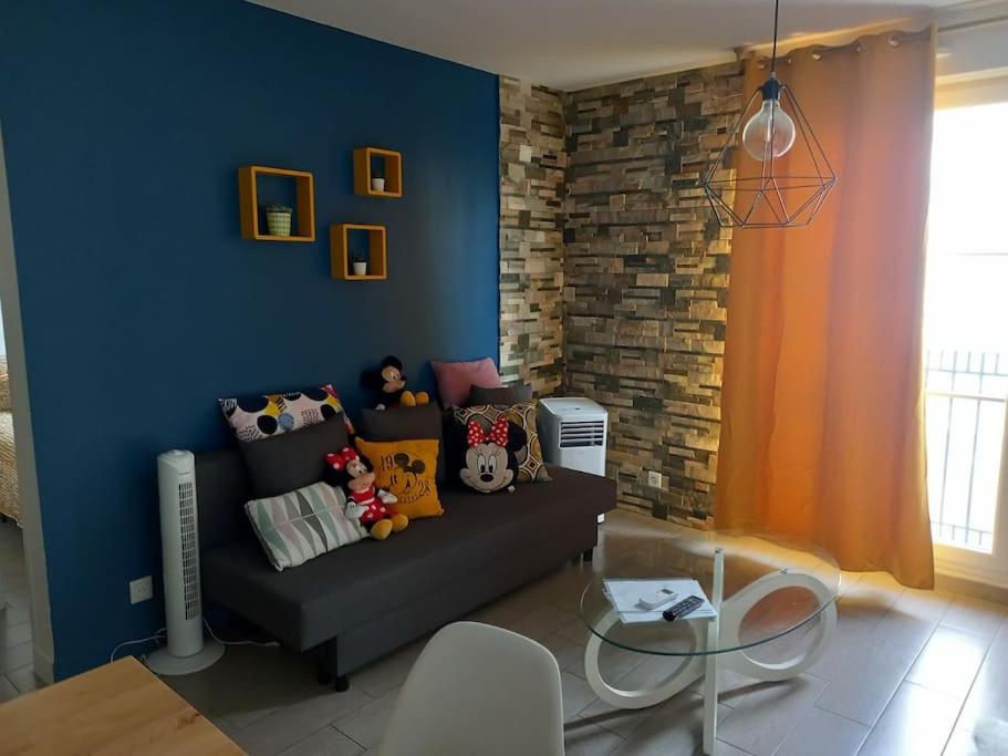un salon avec un canapé et un mur bleu dans l'établissement DISNEYLAND PARIS DINA 2 rooms, à Serris