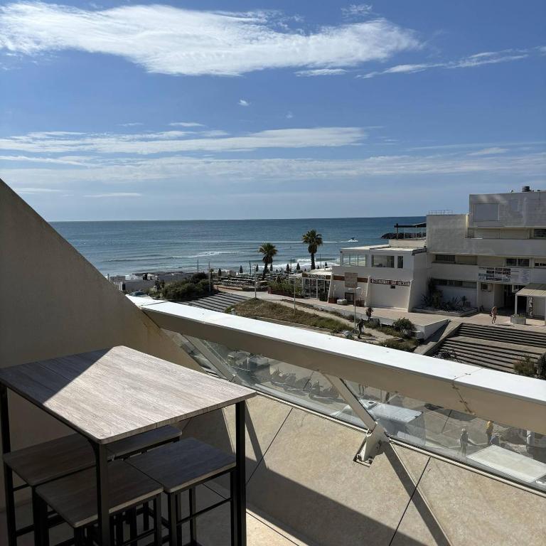 un balcon avec une table et une vue sur l'océan dans l'établissement Studio Luxe vue mer Persuasion - Héliopolis D 8 - 2 personnes, au Cap d'Agde