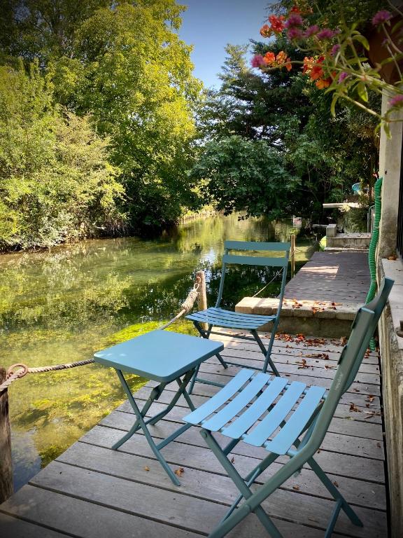 deux chaises et une table sur un quai au bord d'une rivière dans l'établissement Les Capucines, à LʼIsle-sur-la-Sorgue