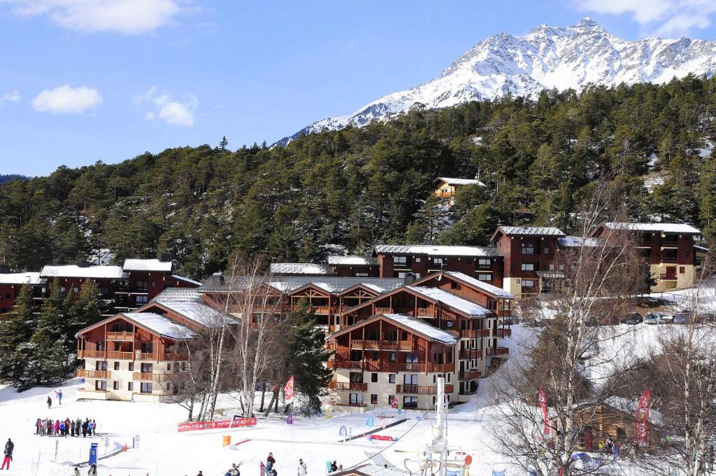 un lodge de ski en face d'une montagne enneigée dans l'établissement Résidence Goélia Les Balcons d'Anaïs, à La Norma