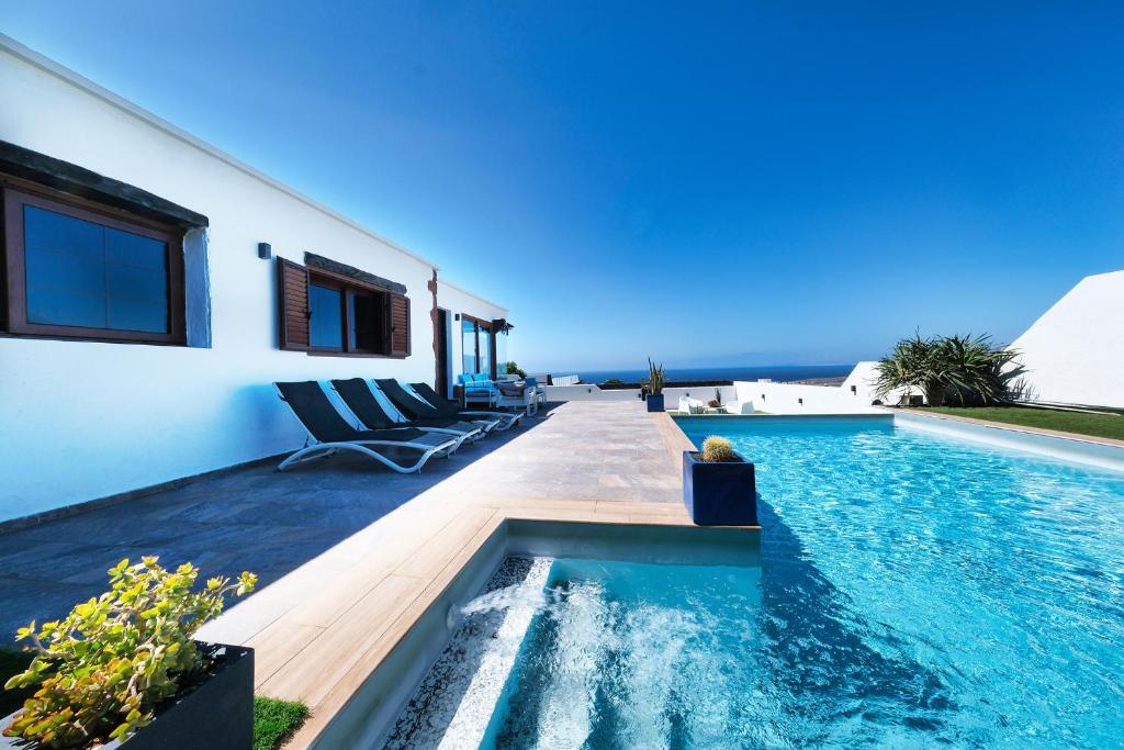 a villa with a swimming pool and a house at Villa Macher Piscina y Bar piscina in Tías