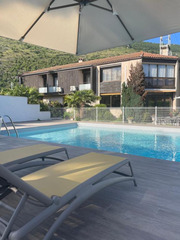 a swimming pool with a chair and an umbrella at H&ocirc;tel Pyr&egrave;ne in Foix