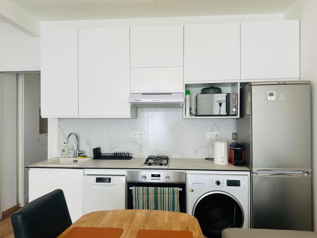 - une cuisine avec des placards blancs, une table et un lave-vaisselle dans l'établissement 3 lits, 2 pièces proche de la rue Mouffetard, à Paris