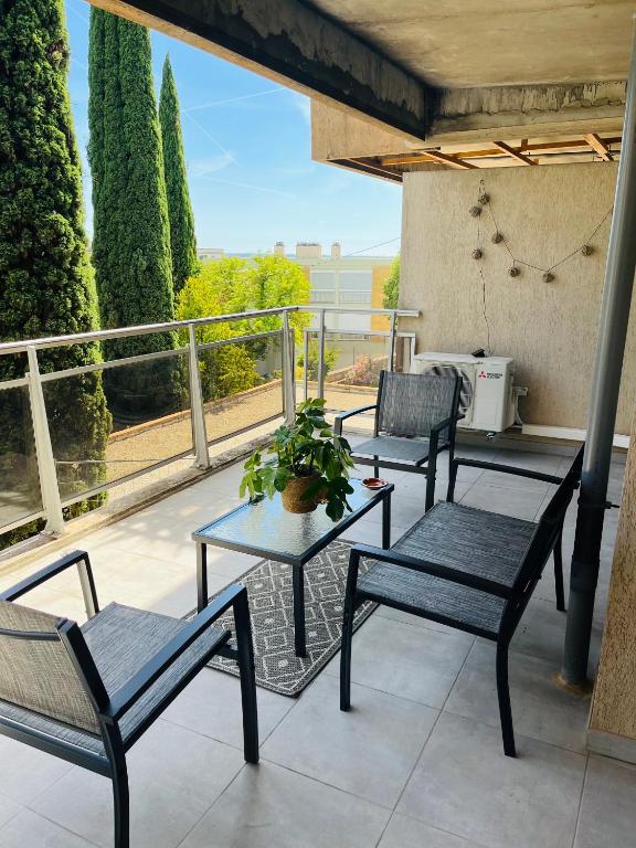 un patio avec trois chaises et une table sur un balcon dans l'établissement Le petit Aixois - Parking, à Aix-en-Provence