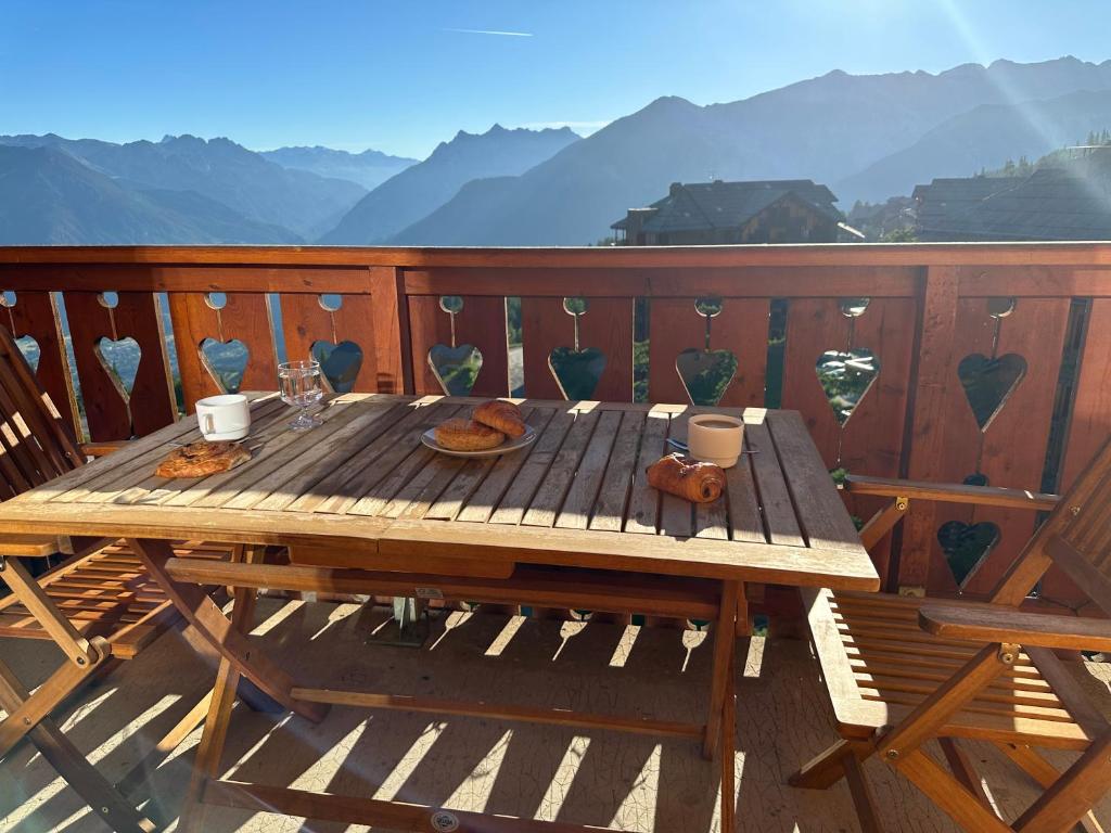 - une table en bois sur une terrasse avec vue sur les montagnes dans l'établissement Risoul duplex 48m2 avec piscine et sauna, à Risoul