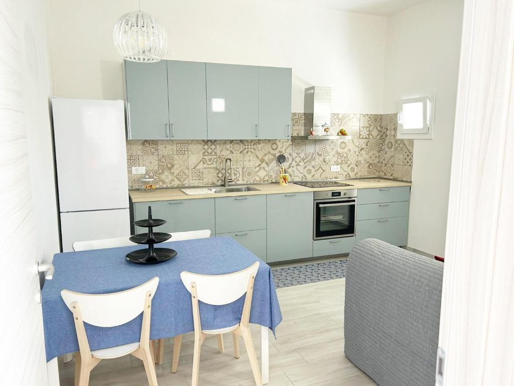 Casa Giannina a Marina di Cecina by Zoom In Earth في مارينا دي سيسينا: مطبخ مع طاولة زرقاء ودواليب بيضاء