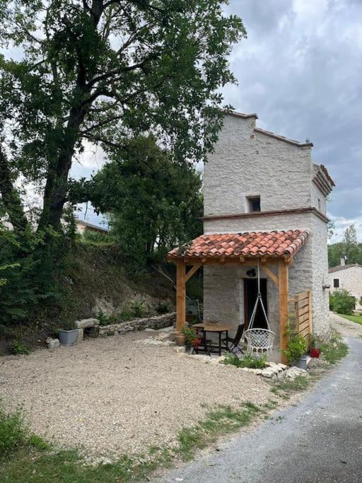 un petit bâtiment avec un porche et un banc dans l'établissement Pradelles, à Castelnau-de-Lévis