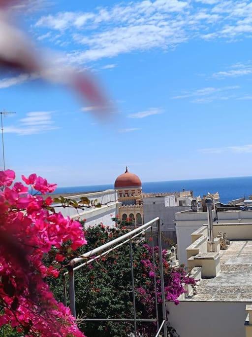 a view of a building with a clock tower and flowers at Adelè posto tranquillo al centro del paese in Santa Cesarea Terme