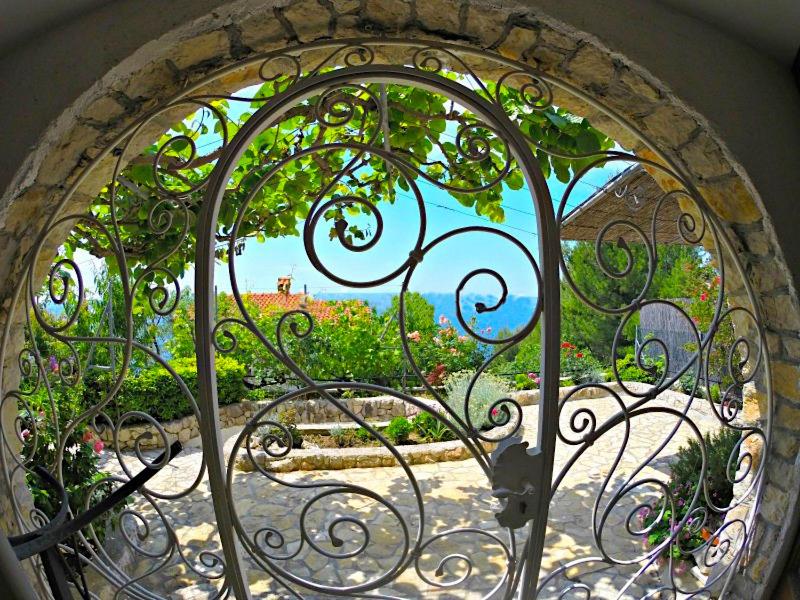 a view of a garden through a metal gate at Villa Bugenvilla in Lokva Rogoznica