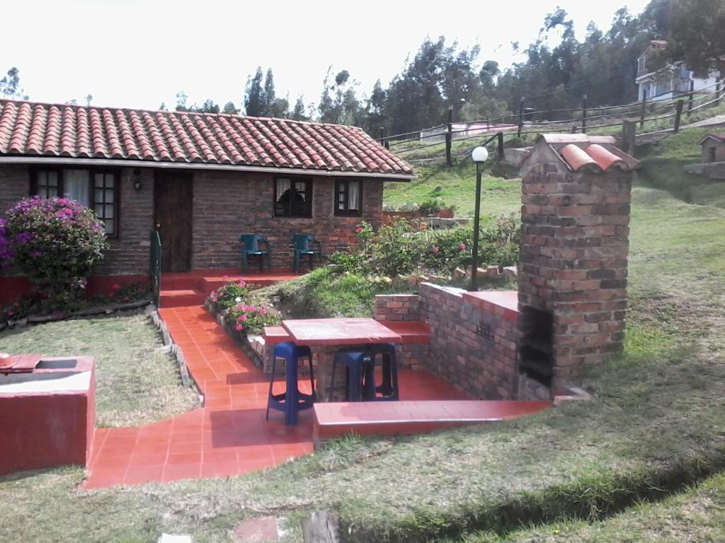 a brick house with a picnic table in front of it at Granja el Milagro - Cabañas Campestres in Tibasosa