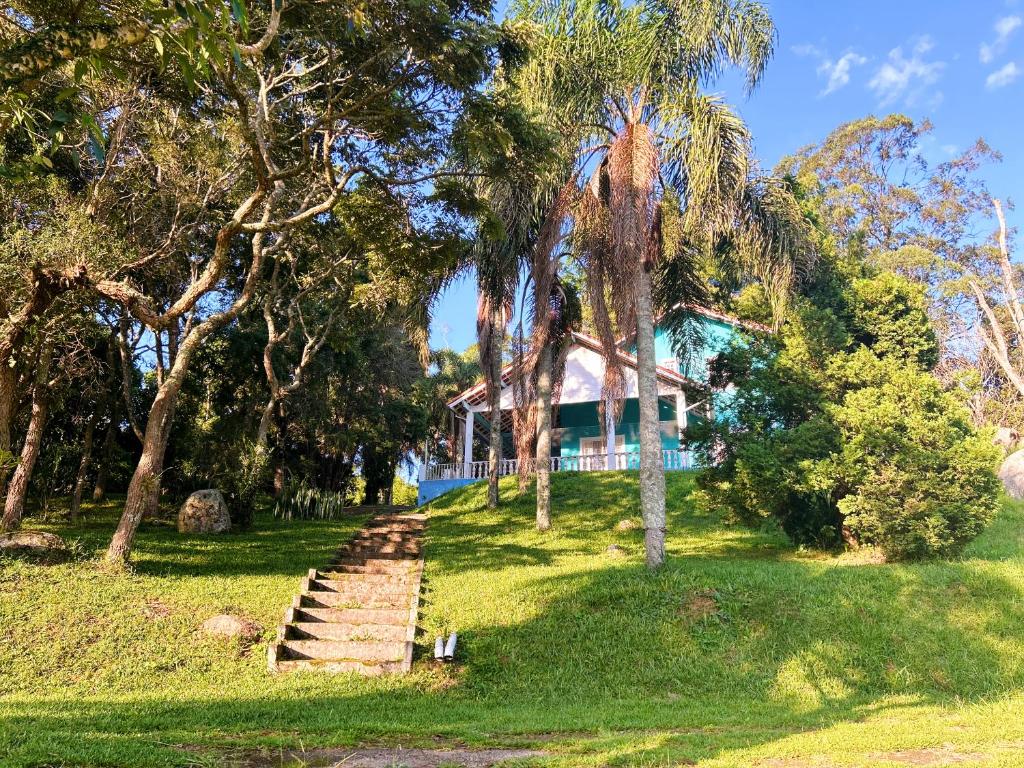 a house with palm trees and stairs in the grass at Chalé aconchegante em São Roque in São Roque