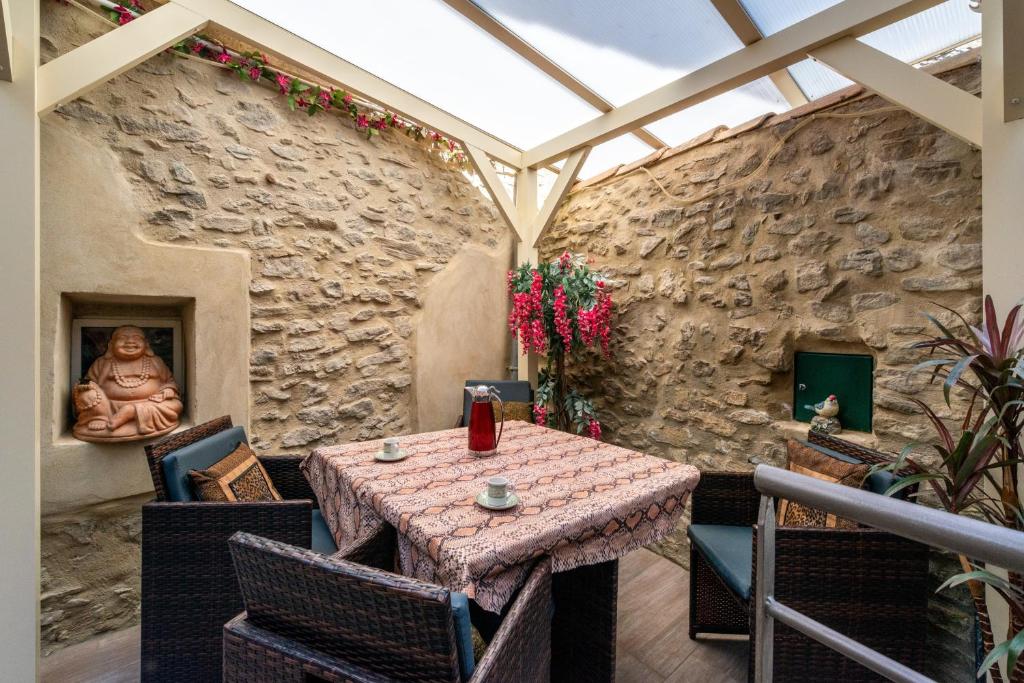 une salle à manger avec une table et un mur en pierre dans l'établissement Le Chardonneret Élégant - Maison pour 4 climatisée, à La Livinière