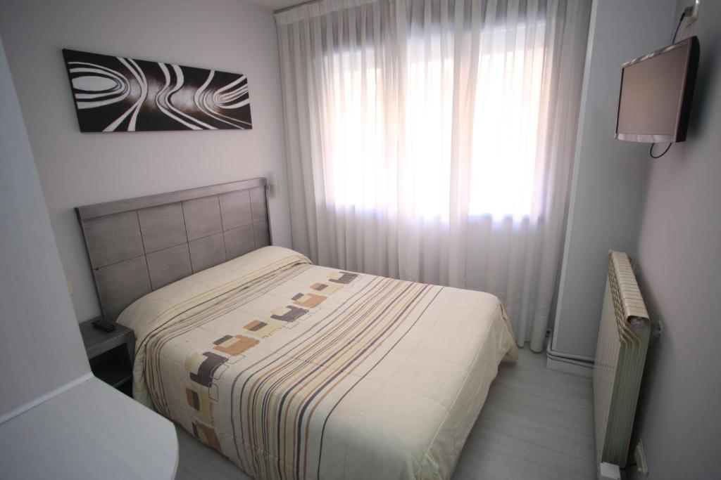 Habitación pequeña con cama y ventana en Hostal Santa Barbara, en Soria