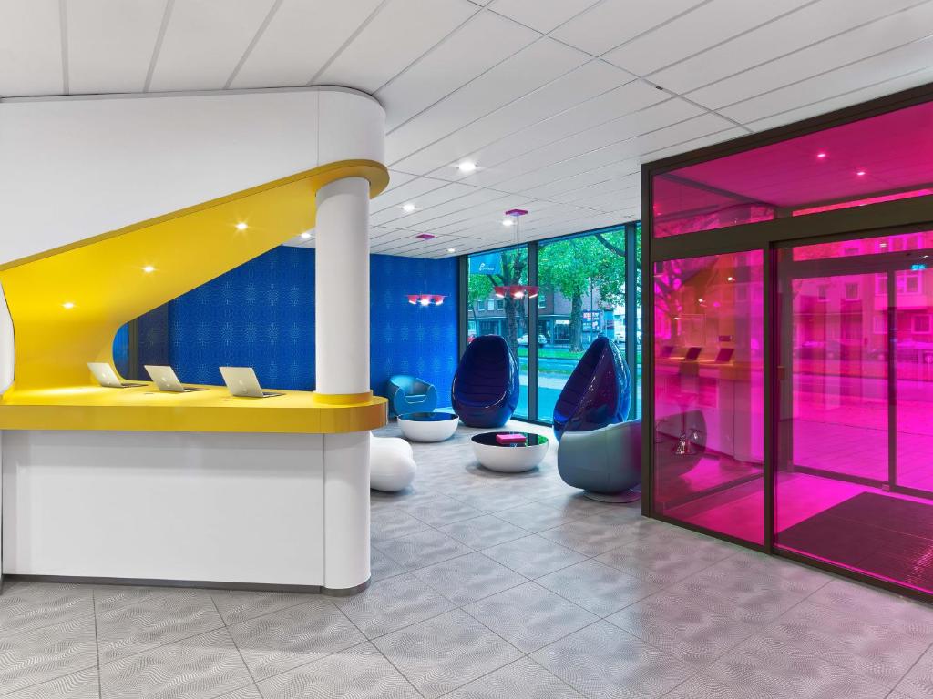 a lobby with blue chairs and a yellow counter at prizeotel Hannover-City in Hannover