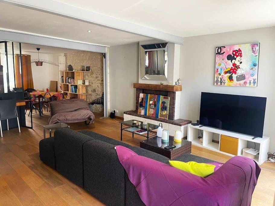 un salon avec un canapé et une télévision à écran plat dans l'établissement Jolie maison proche du centre ville, à La Rochelle