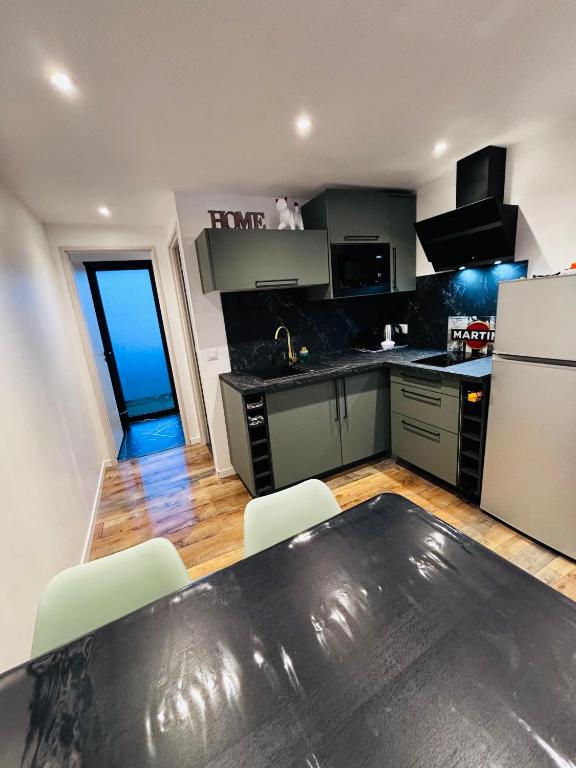 Il comprend une cuisine équipée de comptoirs noirs et d'un réfrigérateur blanc. dans l'établissement Logement du Sud avec Jacuzzi, à Sommières