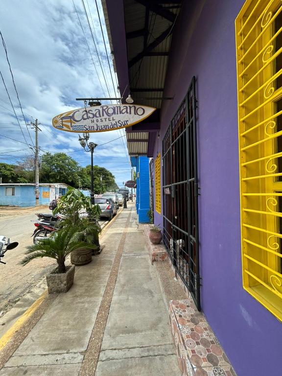 un edificio púrpura con un letrero para un restaurante en Casa Romano Hostel, en San Juan del Sur