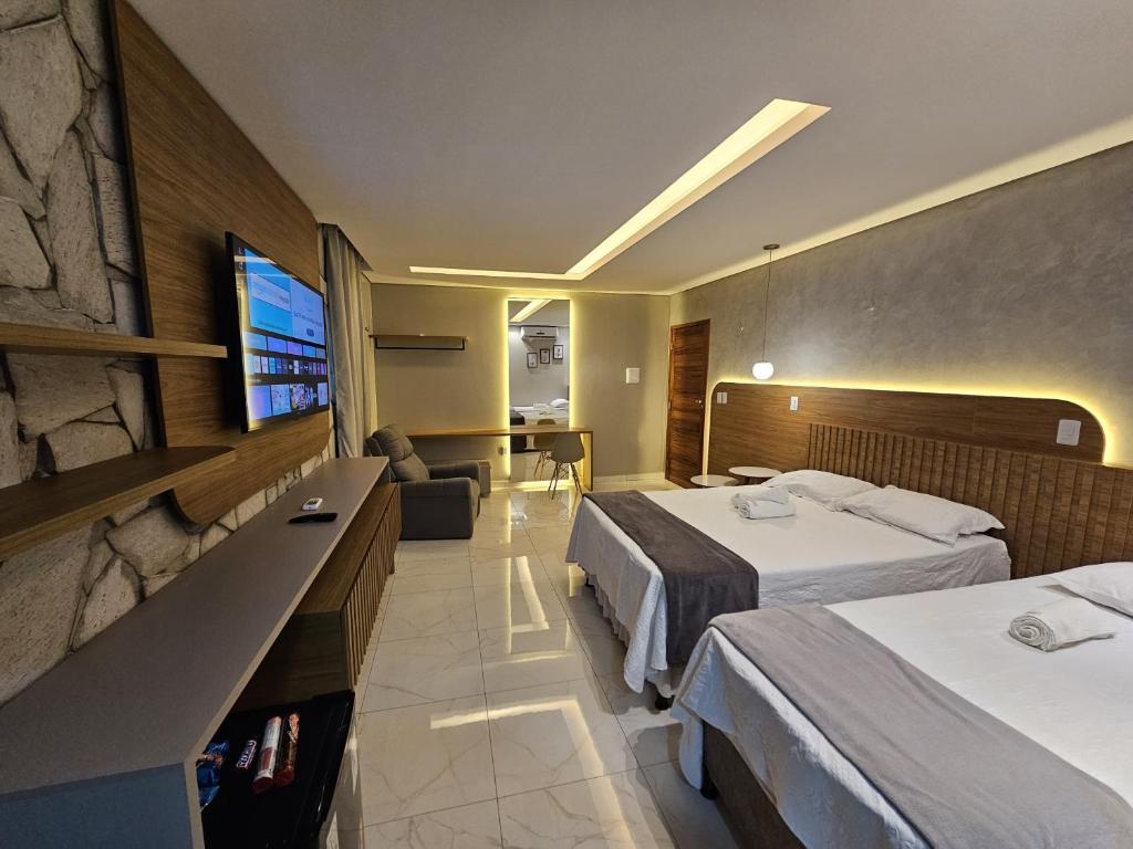 a hotel room with two beds and a tv at Rancho Parati in Martins