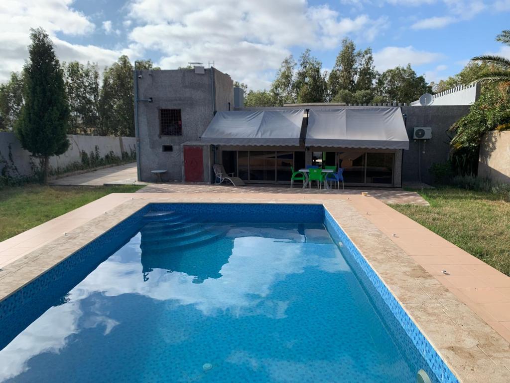 a blue swimming pool with a building in the background at Villa avec piscine in Safi