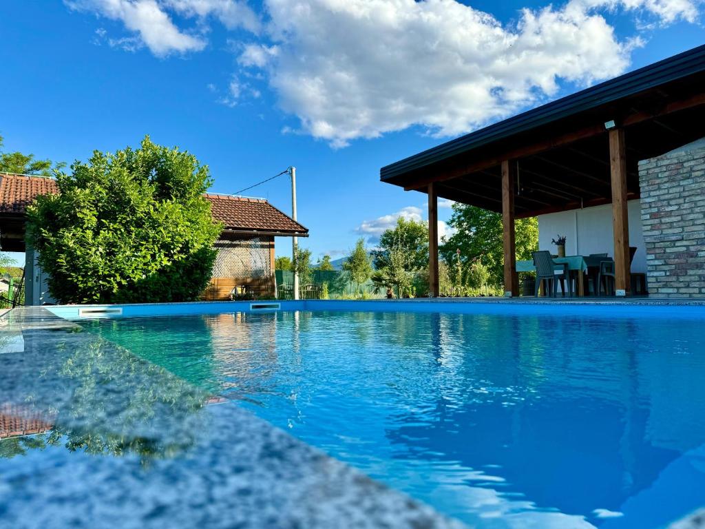 a swimming pool with blue water and a house at Crystal pool in Bihać