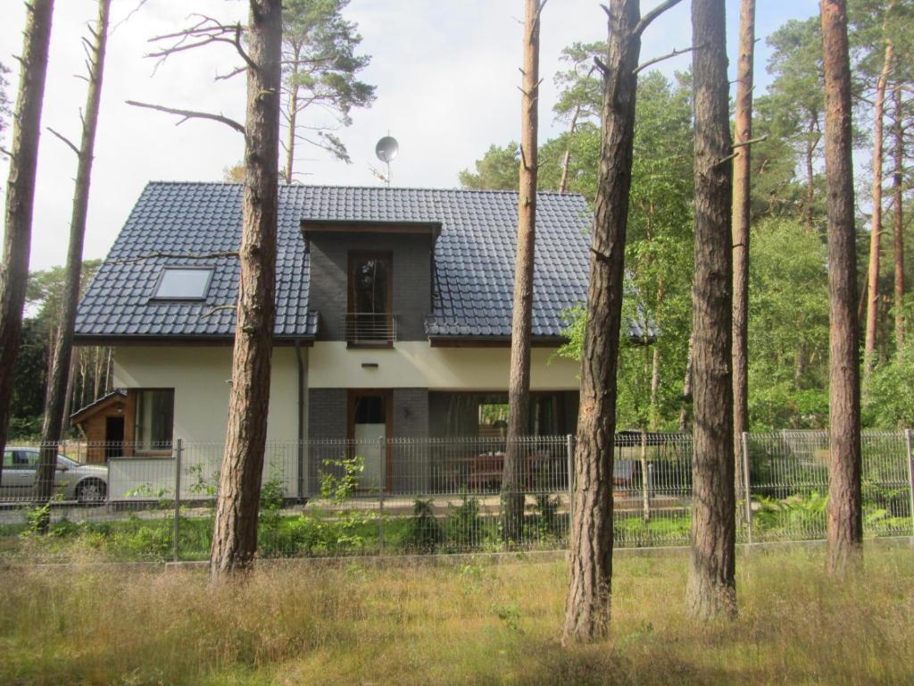 a house behind a fence with trees at Amadea in Łukęcin