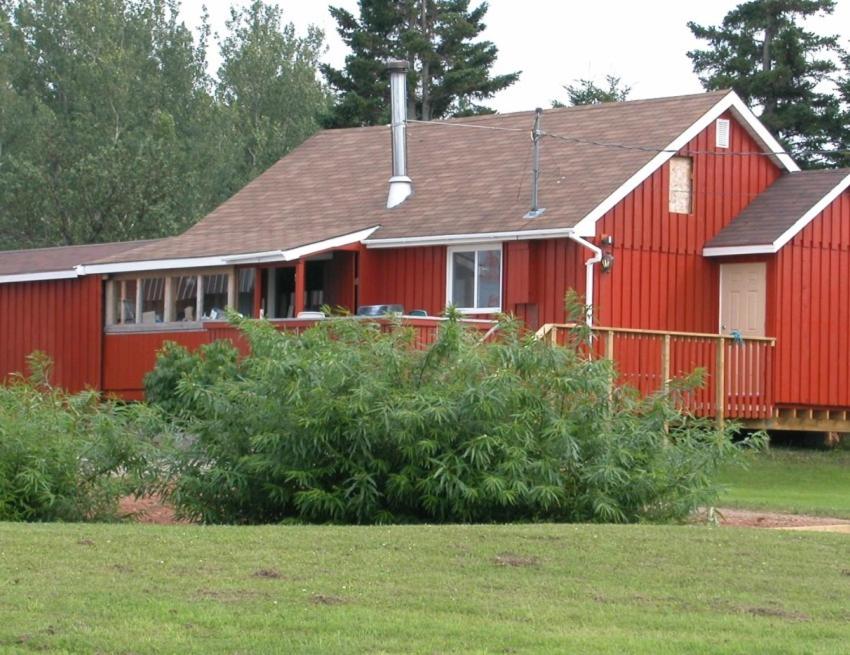 a red house with a red fence in a field at Waterview B&B in Pictou
