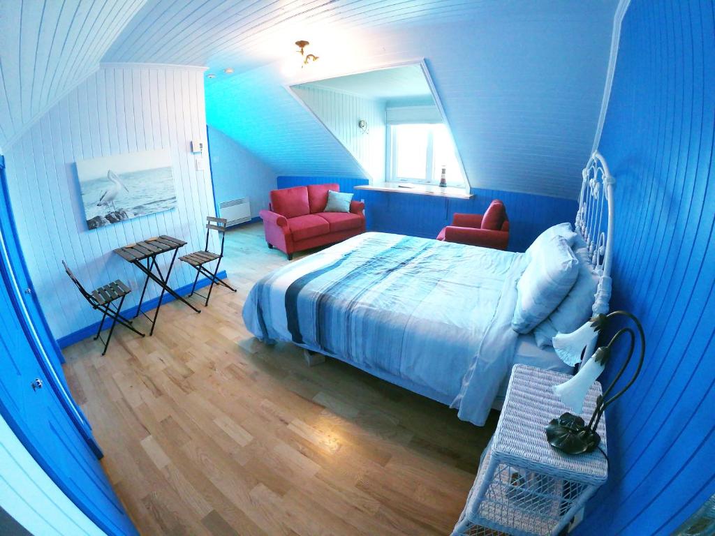 a bedroom with blue walls and a bed and a table at Chez Caro et Sylvain in Rimouski