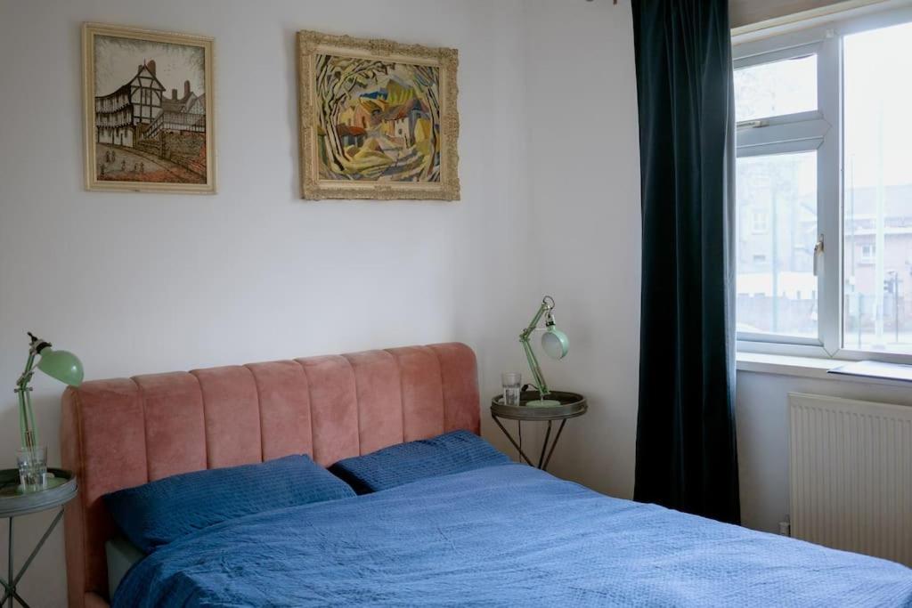 una camera da letto con un letto con lenzuola blu e una finestra di Comfy 1-Bed Flat Near Hospital & Station a Londra