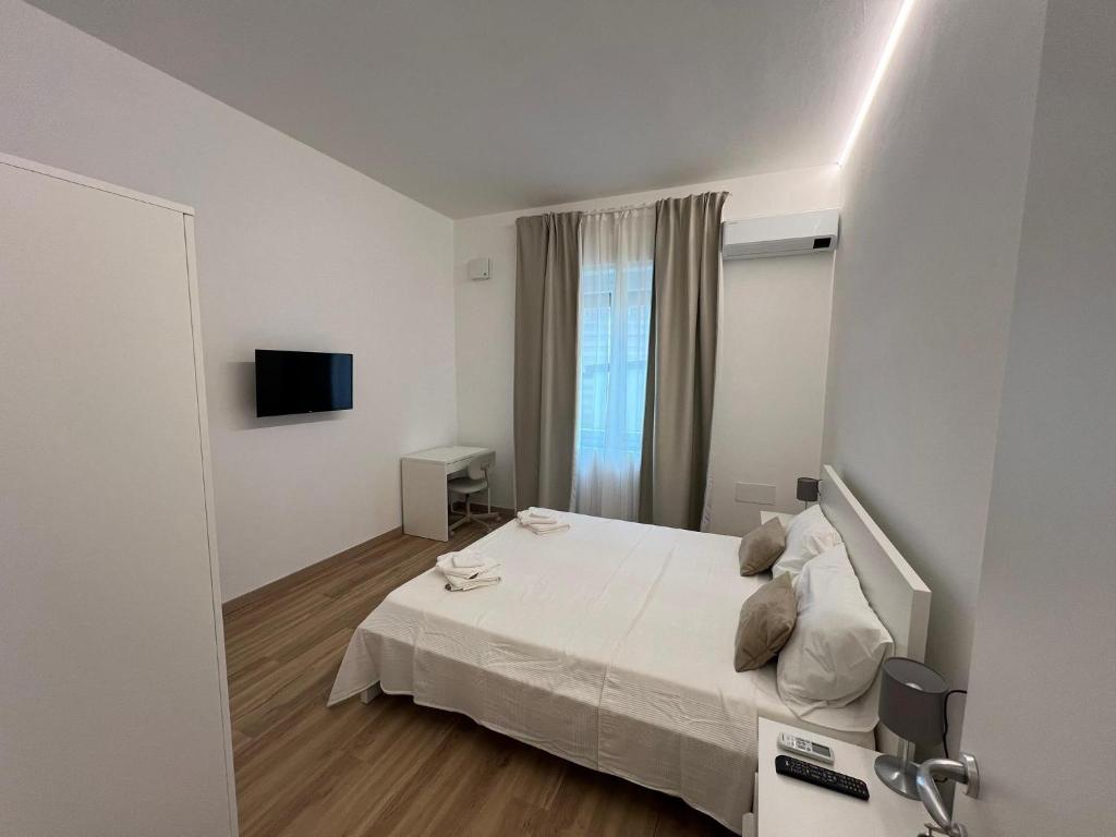 una camera da letto bianca con un letto e una televisione di Gabriellihome a Pescara