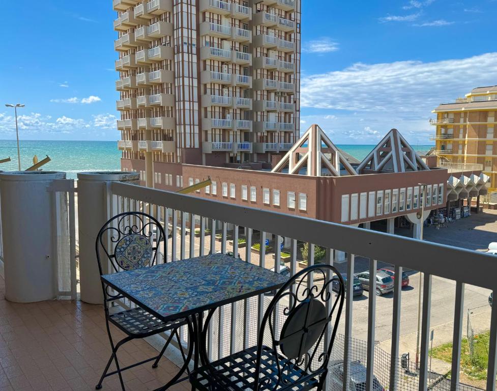 a balcony with a table and chairs and the ocean at NINFEA SEAVIEW APARTMENT - Elegant, Bright and Spacious, Steps from the Sea & Station in Nettuno