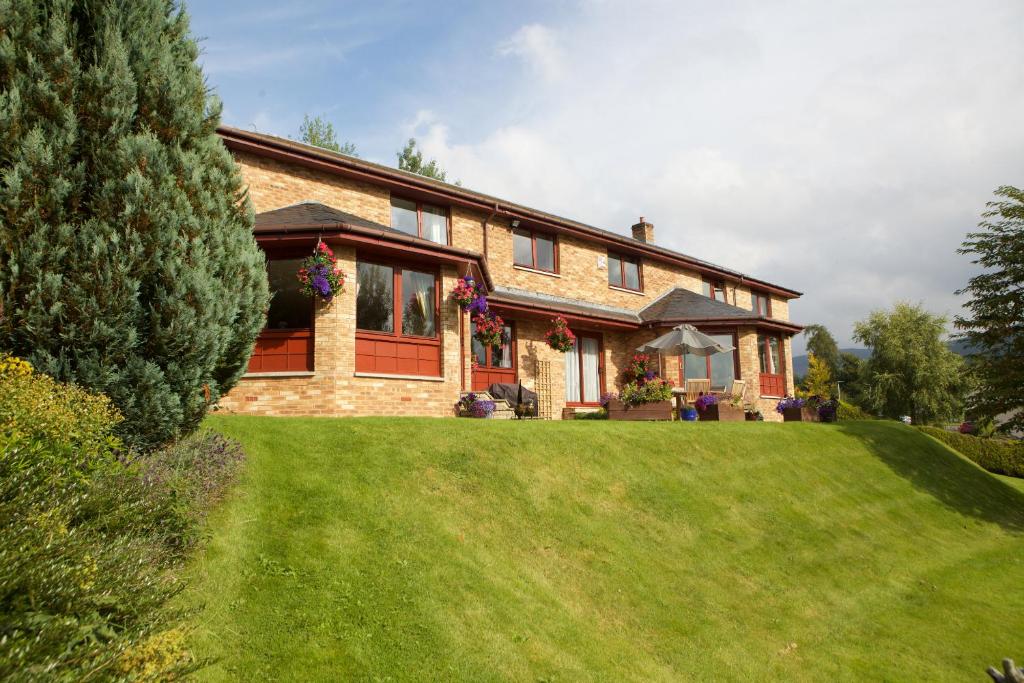 uma grande casa de tijolos com um relvado verde em Glede Knowe Guest House em Innerleithen