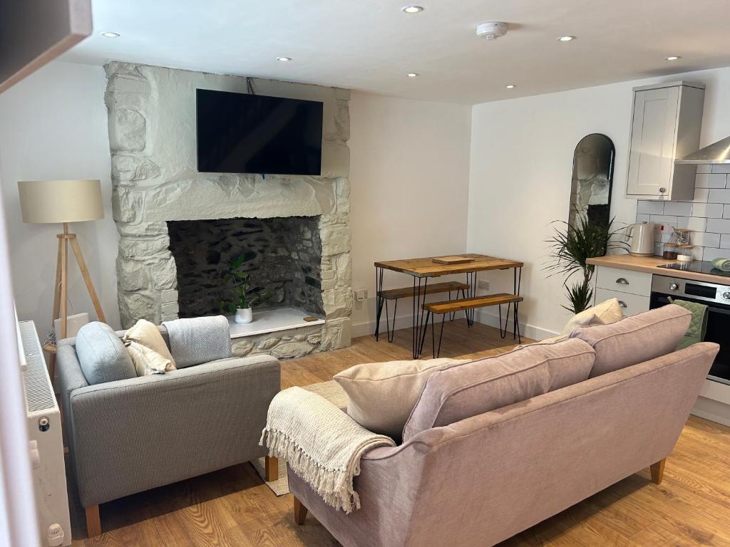 ein Wohnzimmer mit Couch und Kamin in der Unterkunft Cosy modern miners cottage in Llanllechid