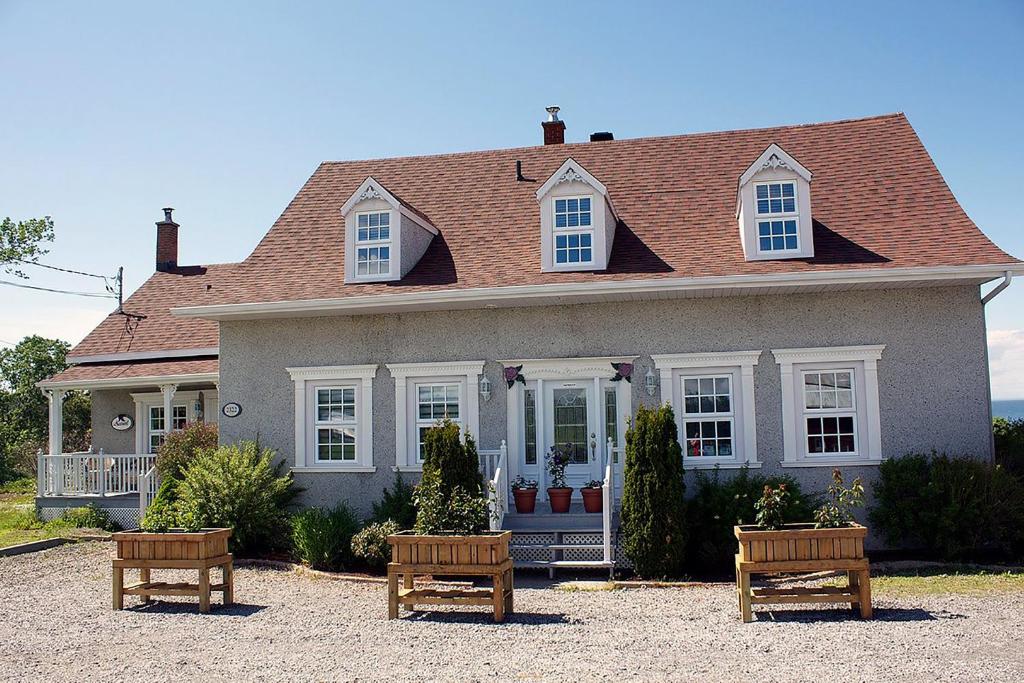 a house with two benches in front of it at Chez Caro et Sylvain in Rimouski