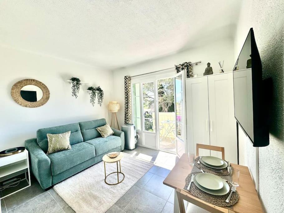un salon avec un canapé bleu et une table dans l'établissement Studio cosy à 5 min de la mer, à Villeneuve-Loubet