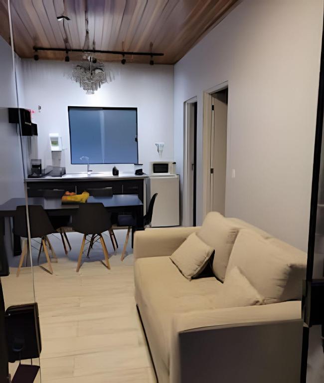 a living room with a couch and a desk at Chalé Dália - Recanto Veky in Campos do Jordão