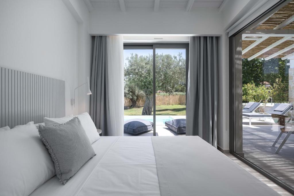 a bedroom with a large white bed and a patio at Astrum Luxury Suites in Vourvourou