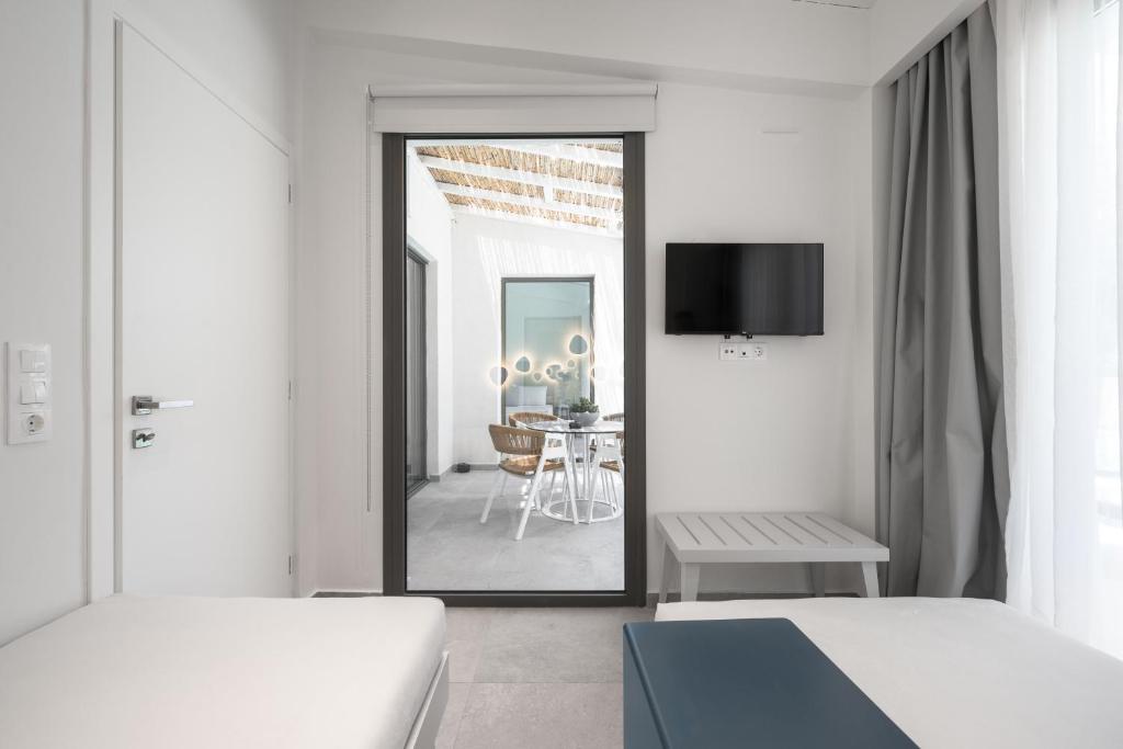 a white room with two beds and a dining room at Astrum Luxury Suites in Vourvourou
