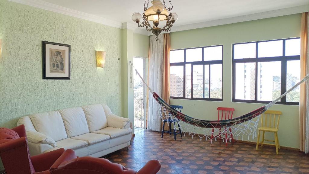 a living room with a couch and a hammock at Apto 2Q Grande e Espaçoso in Curitiba