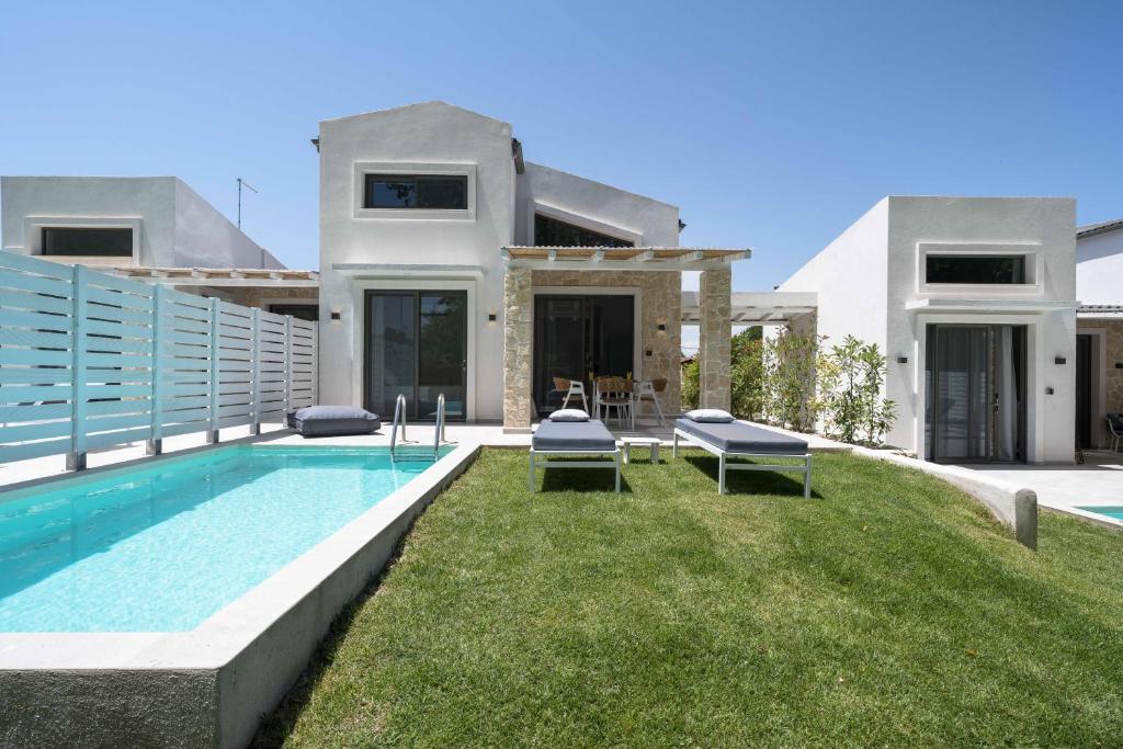 a villa with a swimming pool in front of a house at Astrum Luxury Suites in Vourvourou