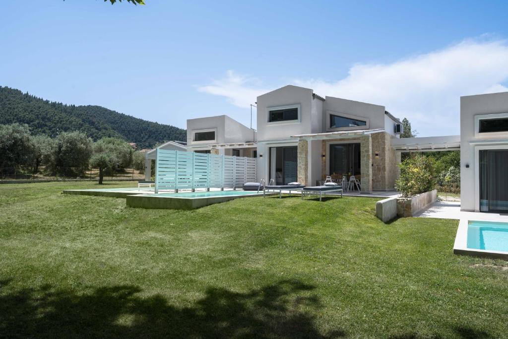 a house with a large yard with a swimming pool at Astrum Luxury Suites in Vourvourou