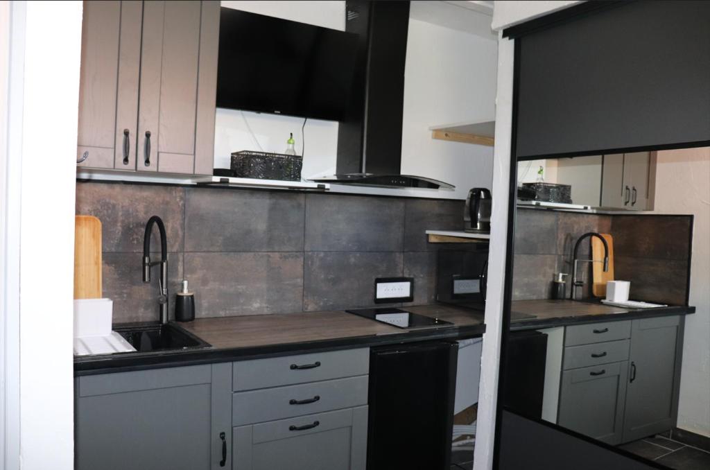 une cuisine avec des armoires blanches et un mur en acier inoxydable dans l'établissement Agréable studio avec sa terrasse extérieure entièrement aménagé à 5 min de la mer, à Cannes