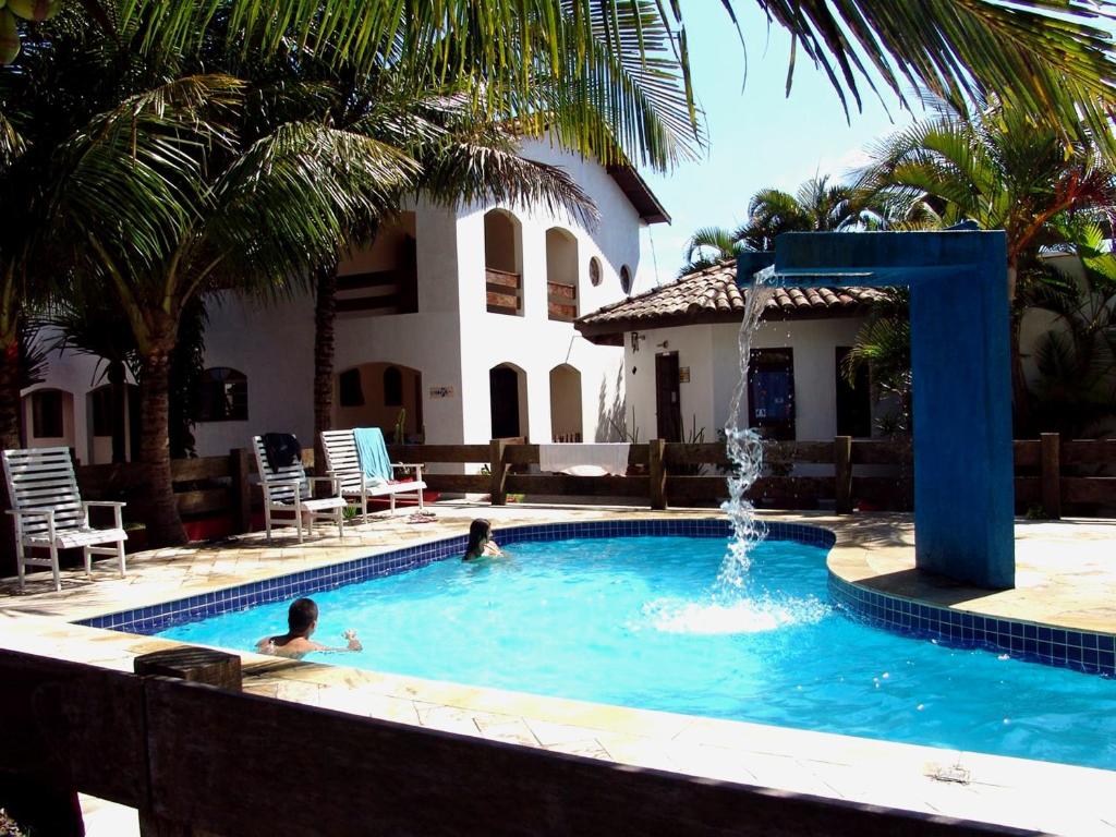 two people swimming in a swimming pool with a fountain at Pousada Icaraí in Ilha Comprida