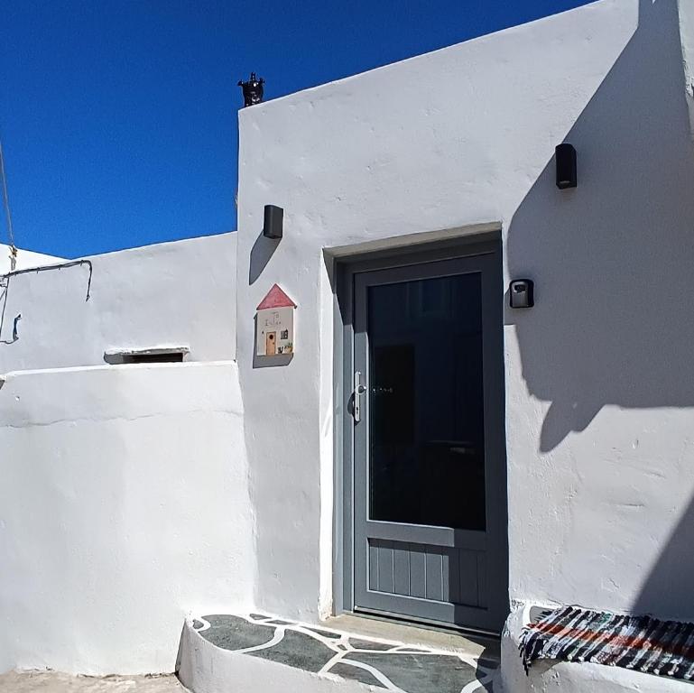 ein weißes Gebäude mit einer Tür, auf der sich ein kleines Haus befindet in der Unterkunft Little House in Káto Petálion
