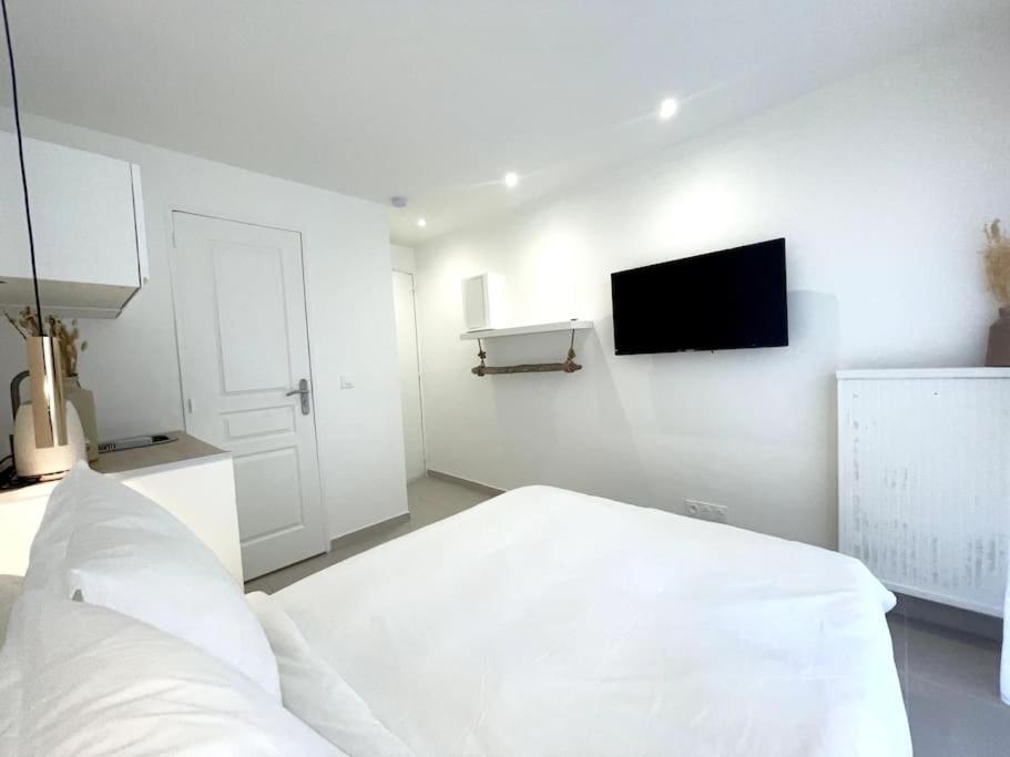 Cette chambre blanche dispose d'un lit et d'une télévision à écran plat. dans l'établissement Nid douillet proche Vieux-Port, à Marseille
