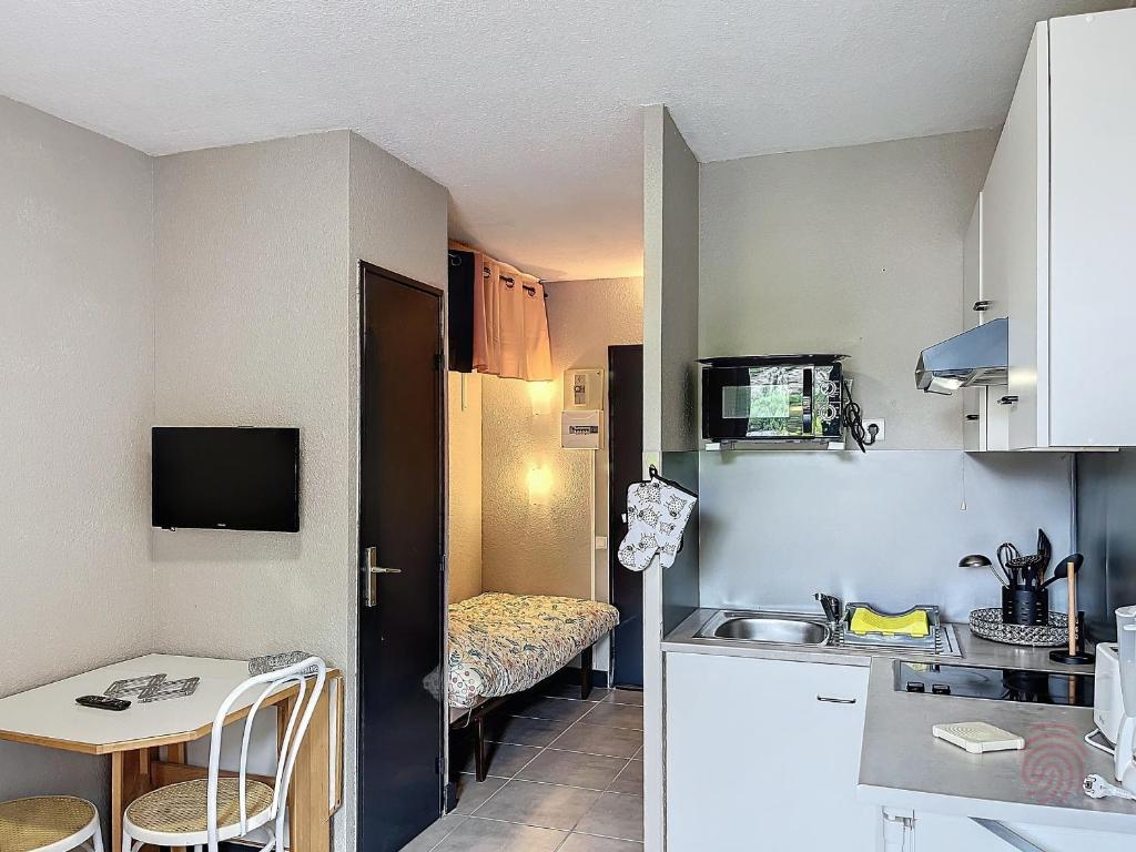 une petite cuisine avec un évier et une table dans l'établissement Studio lumineux proche centre-ville et thermes, balcon, parking, animaux acceptés - FR-1-451-211, à Lamalou-les-Bains